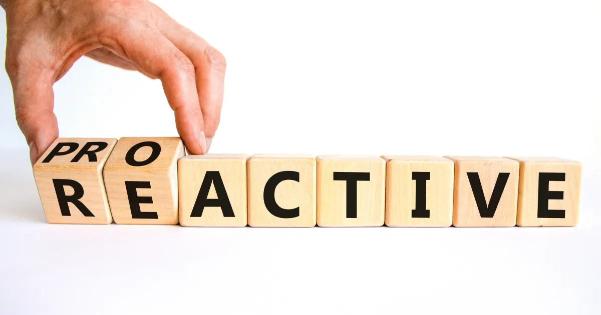 There are blocks with letters that spell "reactive". A hand tips the "re" to "pro" to become proactive. 