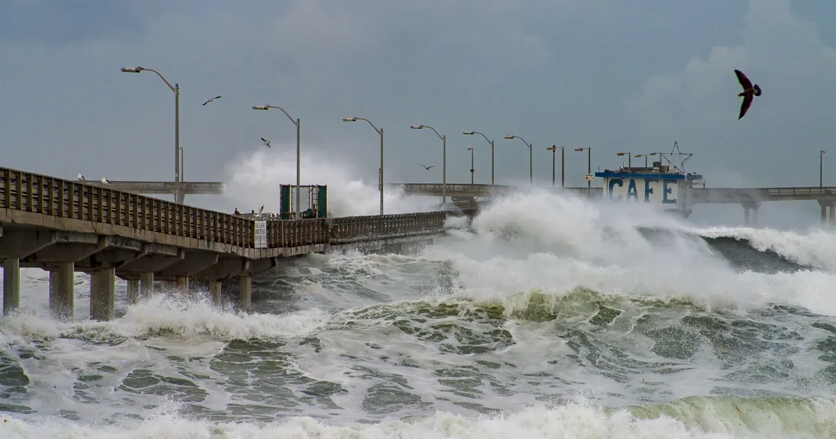 An image showing waves crashing over a pier. 